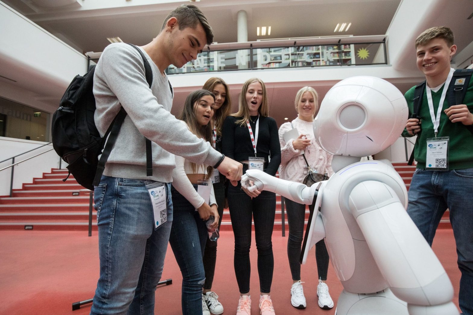 Eine Gruppe von Menschen schüttelt einem Roboter die Hand.