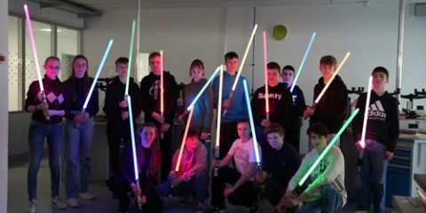 Das Foto zeigt eine Gruppe von 15 Jugendlichen mit ihren bunt leuchtenden Lichtschwertern.