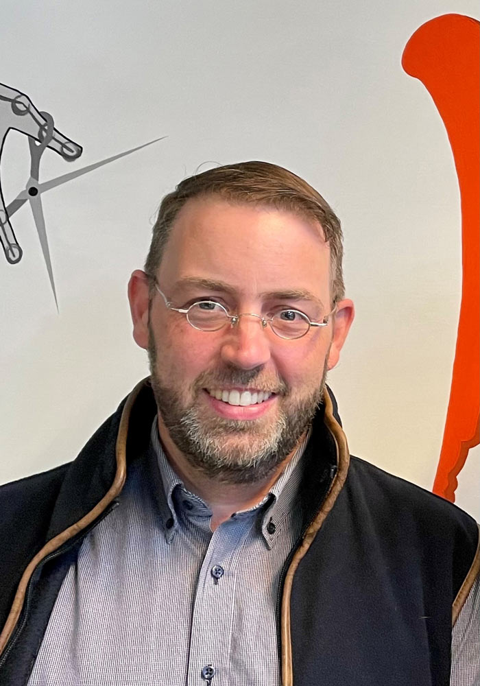 Das Foto zeigt Claas Niehues, einen Mann mit kurzen Haaren, Bart und Brille, der in die Kamera lächelt.