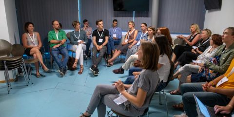 Eine Gruppe von Menschen sitzt auf Stühlen in einem Raum.