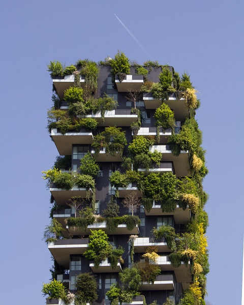Ein modernes Hochhaus. Die Balkone sind üppig grün bepflanzt, so dass das Haus fast wie ein grüner Quader, der in den Himmel reicht, ausssieht.